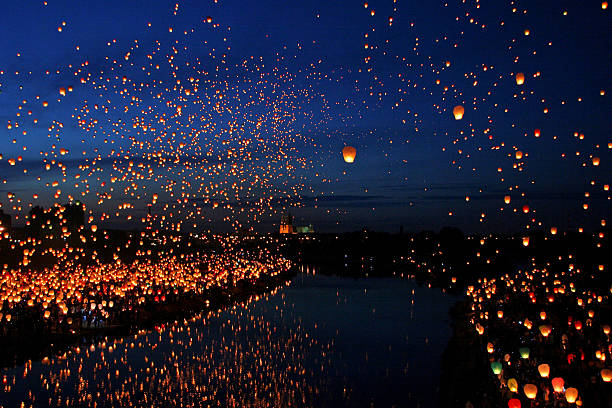 beaucoup de papier fly lanternes à côté de la rivière - ballooning festival photos et images de collection