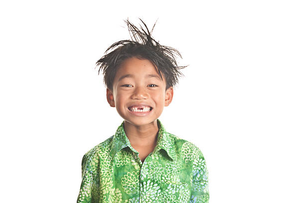 Smiling messy hair child with missing front teeth This adorable 7 year old flashes a bright smile for the camera, revealing two front missing teeth.  Wearing a green Hawaiian shirt, this child encompasses the Spirit of Aloha through his happy and positive facial expression   Image isolated on white filipino ethnicity photos stock pictures, royalty-free photos & images