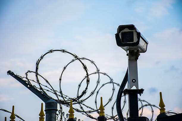 istock Security Camera on Alert Razor Barb Wire Fence Keep Out 487371410