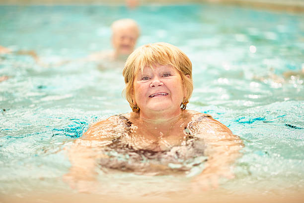 istock senior ladies having fun in pool 487371958