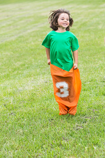 menino se divertindo com batata corrida de saco - child playing sack race sports race - fotografias e filmes do acervo