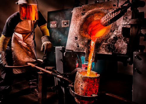Worker pouring liquid metal into crucible.