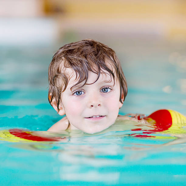 istock little kid boy with swimmies learning to swim 487380512