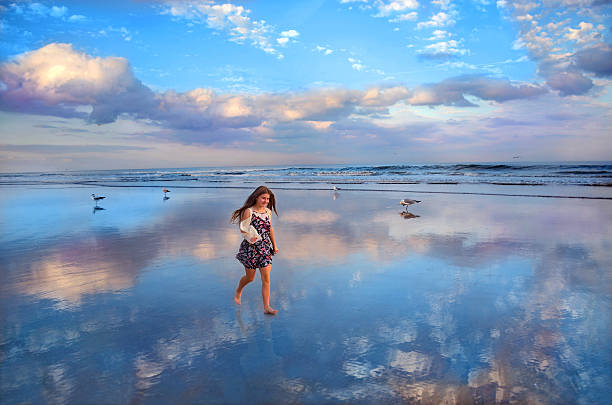 Smiling child walking on beautiful beach. Reflection of beautiful sky and clouds in the water on the beach, Daytona Beach Florida 