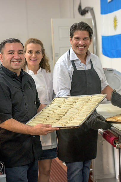 Deli Workers posing Smiling Deli workers posing inside their restaurant holding a tray of raw empanadas argentinian ethnicity photos stock pictures, royalty-free photos & images