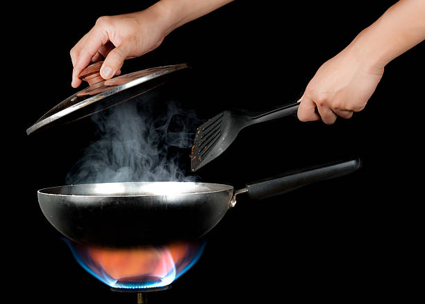 istock hand holding a kitchen spatula and Frying Pan on Burner 487386754
