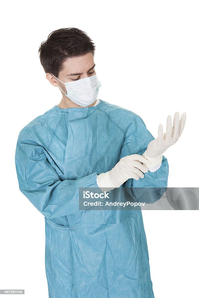 Chirurgo mettendo su guanti chirurgici - Foto stock royalty-free di Adulto