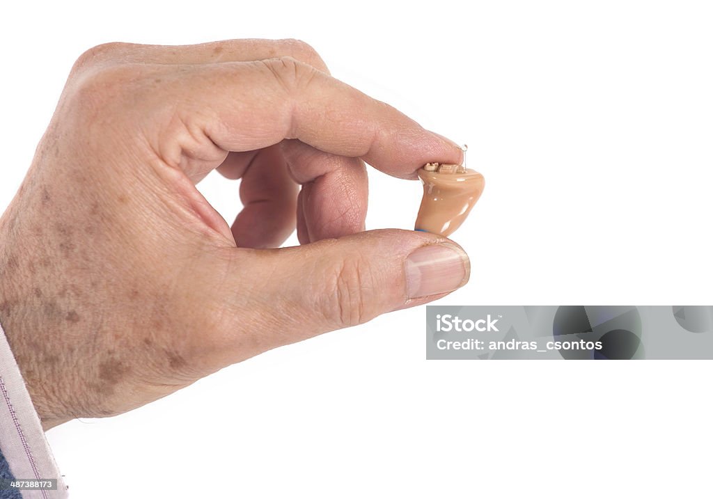 CIC hearing aid between fingers Old man's hand showing a CIC (completely in canal) hearing aid AIDS Stock Photo