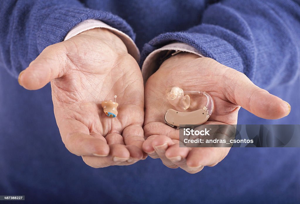CIC and BTE hearing aids Old man's hand showing a CIC (completely in canal) and a BTE (behind the ear) hearing aids AIDS Stock Photo