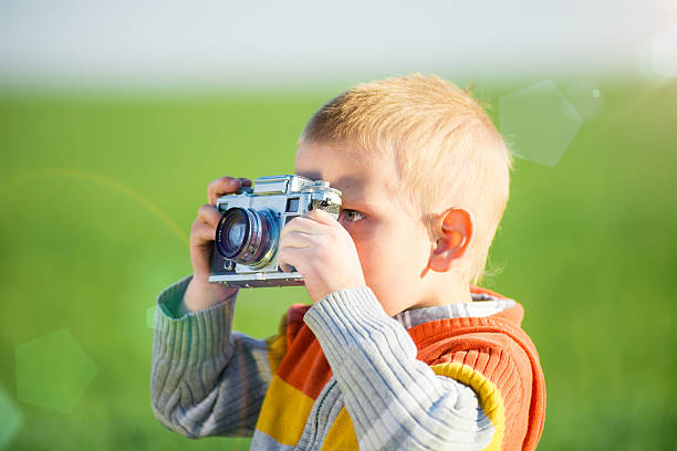 istock Little boy with an old camera shooting outdoor 487390264