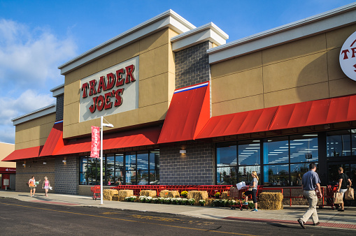 Foxboro, Massachusetts, USA - September 4, 2015: A steady flow of customers enter Trader Joe's with empty hands and exit with overflowing bags and shopping carts. With 457 stores, mostly in California, Trader Joe's  is a market leader in organic and fresh food groceries in the United States.  Some locations, such as this one in Foxboro, Massachusetts also have a wide wine and beer selection.