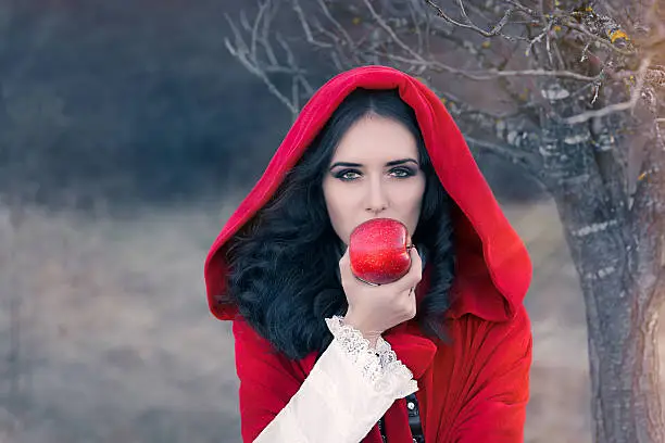 Fairytale image of a beautiful  girl wearing a red hood near the forest