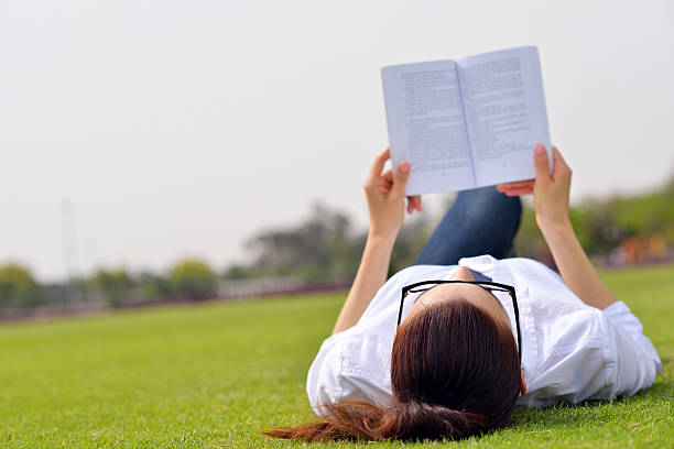 istock Young woman reading a book in the park 487391813