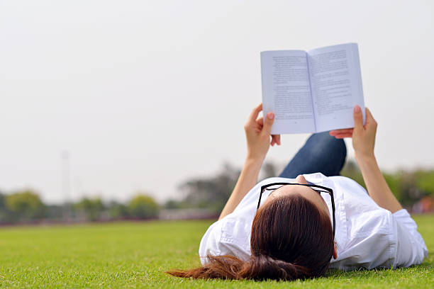 istock Young woman reading a book in the park 487391915