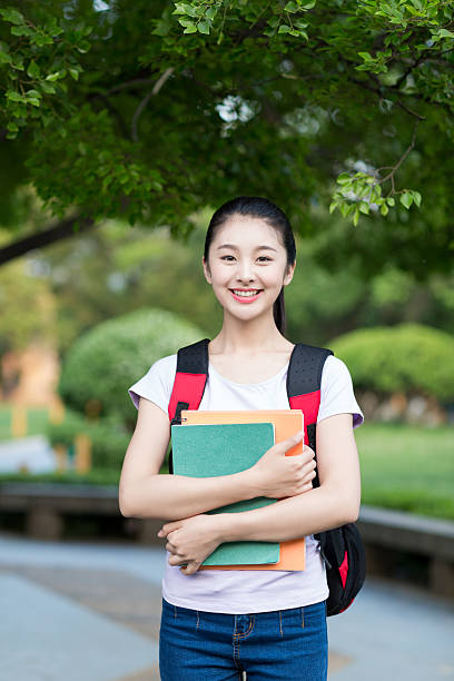 istock female student outdoors holding a notebook and smiling 487394796