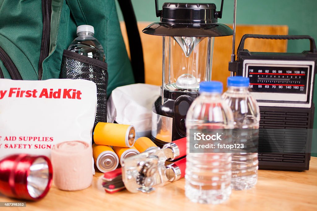 Emergency preparedness natural disaster supplies. Water, flashlight, lantern, batteries. Emergency preparedness supplies. A large pile of supplies to be used in case of a natural disaster (hurricane, flood, earthquake, etc.) including: flashlight, backpack, batteries, water bottles, first aid kit, lantern, radio, can opener, mask.  No people. First Aid Kit Stock Photo