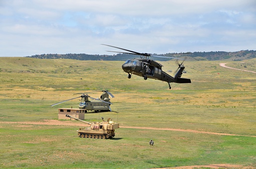 Ft. Carson, CO, USA - June 7, 2014: The Colorado National Guard in partnership with Fort Carson conducted a (CALFEX) combined-arms live-fire exercise and public demonstration at Fort Carson. Blackhawk helicopter with a Chinook helicopter and artilley in the background. 