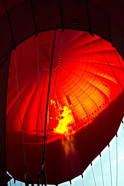istock Bright gas burner flame against red hot air balloon fabric 487407042