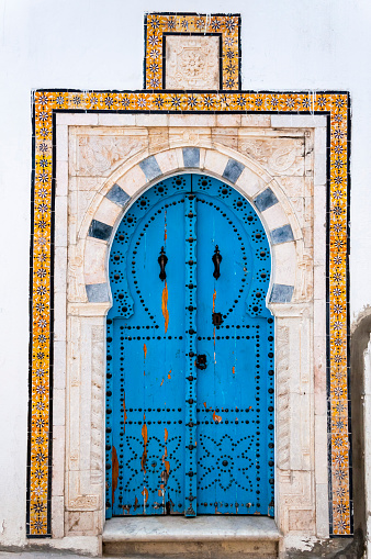 Traditional Tunisian architecture with white houses and blue painted ornate windows and doors in Sidi Bou Said, a popular touristic spot near Tunis, Tunisia.