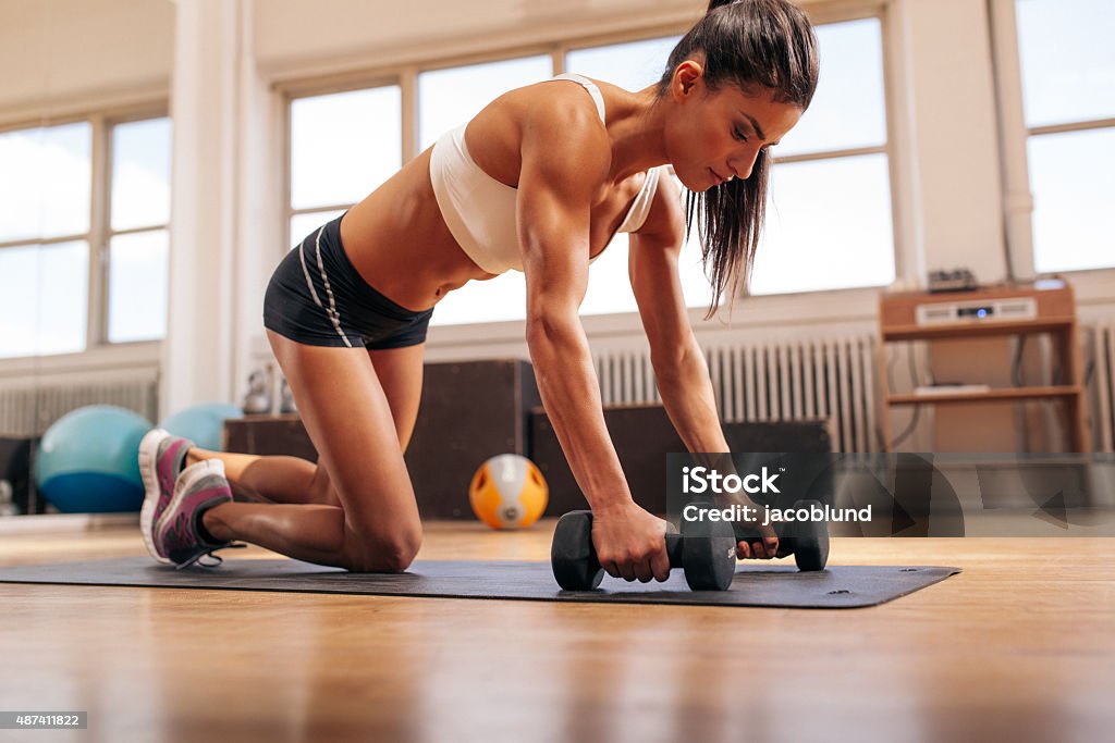 Powerful woman doing push-ups on dumbbells Powerful woman doing push-ups on dumbbells in gym. Muscular female exercising in health club. 2015 Stock Photo