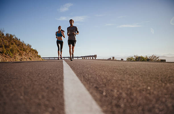 istock Two young people running on country road 487417138