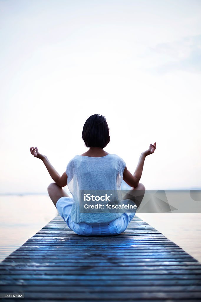 woman making yoga in front of the sea Lake Stock Photo