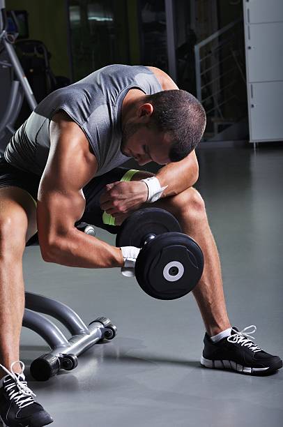 istock Handsome Muscular Male Model in a Sitting Position Doing Biceps 487418494