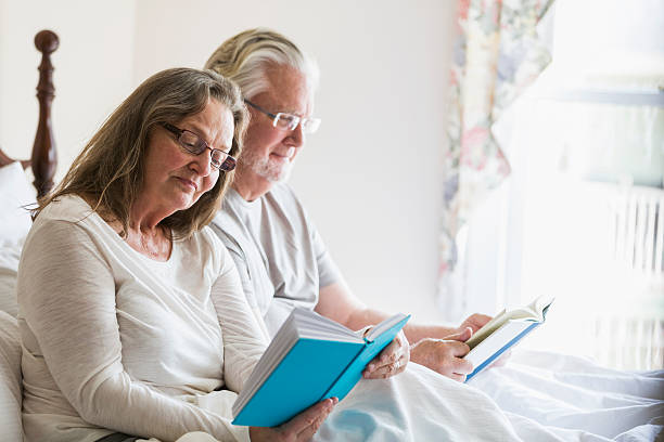 istock Senior couple sitting in bed reading books 487419756