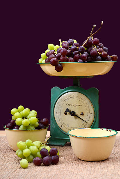 Weighing grapes on vintage scales. Weighing grapes on vintage scale with old enamel bowls on burlap covered pine table. vintage kitchen scale with fruit stock pictures, royalty-free photos & images