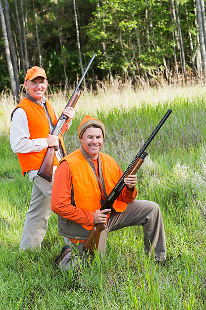 istock Two hunters with shotguns in tall grass by woods 487422882