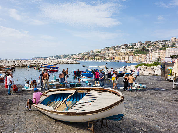 Naples, Italy - September 6, 2015: Fishermen in Naples city, some people walking around at morning to buy fresh fish. Photo taken in Naples sea promenade, the hill of Posillipo in background. 
