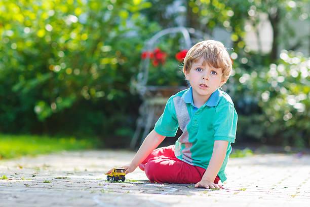 poco niño niño jugando con coche de juguete, al aire libre - car child teamwork sports race fotografías e imágenes de stock