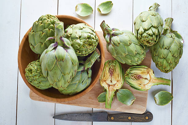 Fresh artichokes to cook Fresh artichokes on the table of the kitchen to be cooked artichoke stock pictures, royalty-free photos & images