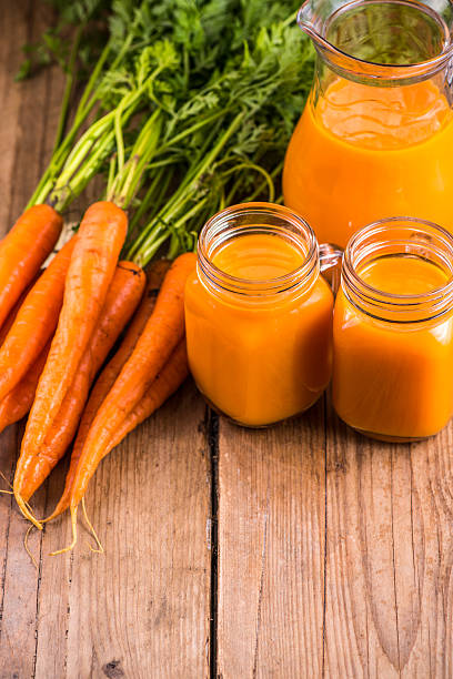 istock Carrot juice in mason jar on wooden background 487424018