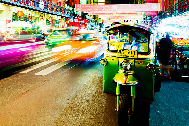 Colourful Tuk-tuk moving past the Grand Palace, Bangkok, Thailand.