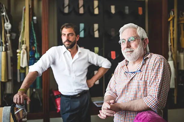 Mature man with his son in their artisanal handicraft traditional textile factory