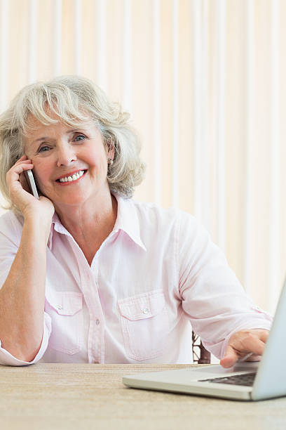 istock Smiling senior woman using mobile phone and laptop 487442067
