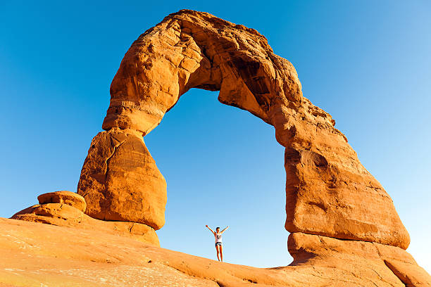 Young woman standing under Delicate Arch in Arches National Park, Utah, USA:Nikon D3x