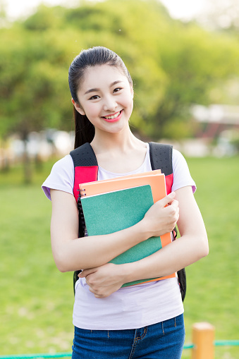 student girl outside in summer park smiling happy. asian female college or university student.