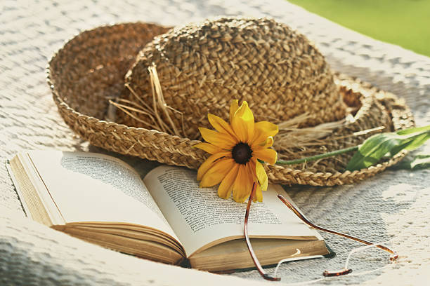 istock Close up of straw hat glasses and book on  hammock 487450970
