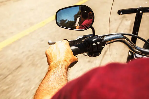 Back view of guy on chopper, with handlebars and rear-view mirror,on the street