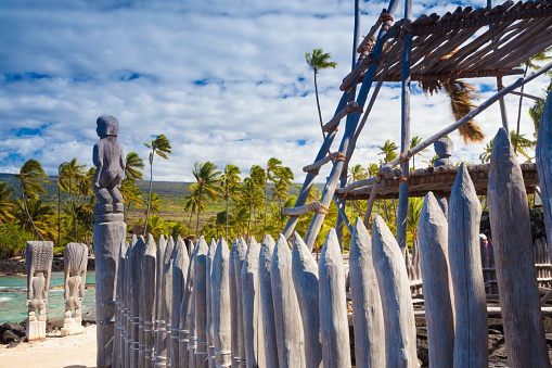 Old wooden structures and protection idols at ancient Hawaiian site Puuhonua O Honaunau National Historical Park on Big Island, Hawaii