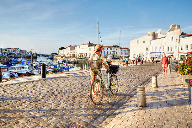 Woman cycling on harbour at St Martin-De-Re stock photo