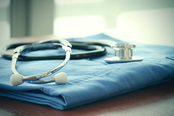 istock Stethoscope with blue doctor coat on wooden table 487457962