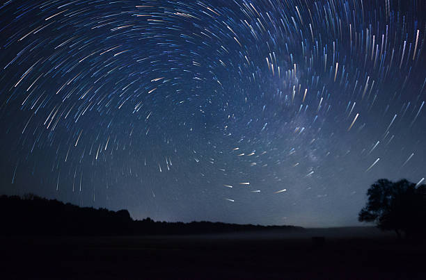 istock beautiful night sky, spiral star trails and the forest 487458456