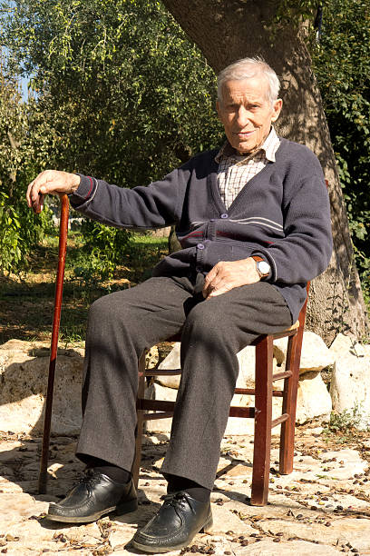 Old man sitting outdoors in garden home,under hot sun of autumn,in Puglia land.