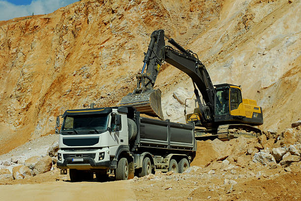 istock Yellow excavator loading stones in a truck 487463818