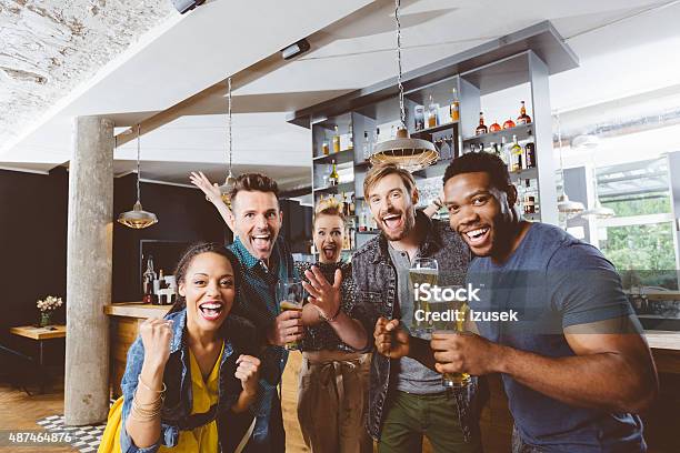 Friends Cheering With Beer In A Pub Stock Photo - Download Image Now - Sport, Bar - Drink Establishment, Bar Counter