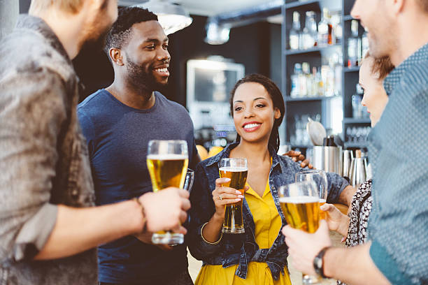 Multi ethnic friend having party in a pub Multi ethnic group of happy friends having party in a pub, drinking beer, talking. Focus on afro american couple.  black people bar stock pictures, royalty-free photos & images