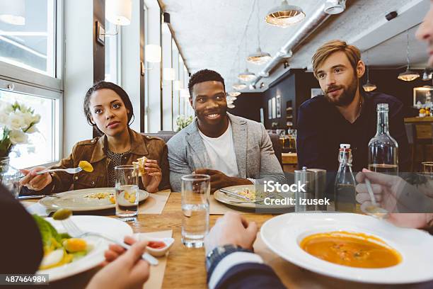 Multi Ethnic Group Of Friends Eating Dinner In A Restaurant Stock Photo - Download Image Now